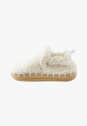 Zapato de bebé de color crema suave con textura de forro polar, suela marrón claro y bordes cosidos, diseñado para ofrecer calidez y comodidad.