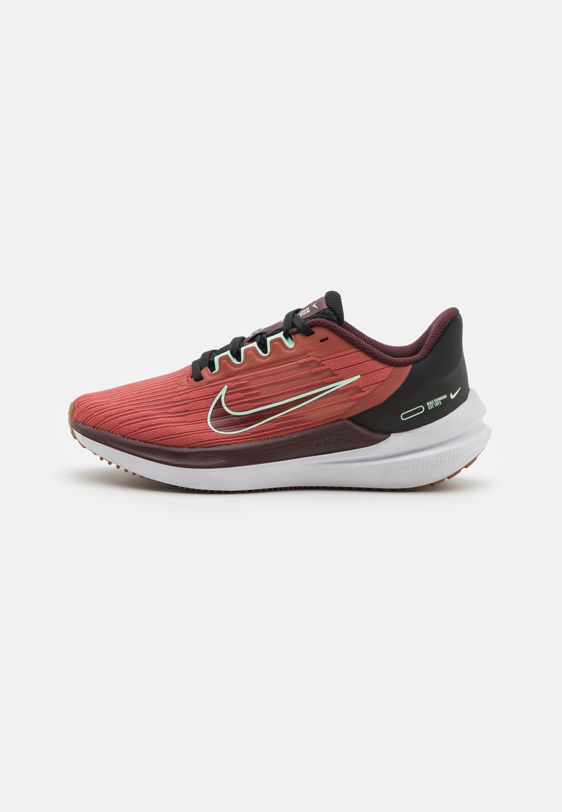 Scarpe da corsa Nike con tomaia rossa e nera in tessuto texturizzato, un'intersuola bianca imbottita e una suola in gomma con motivi di trazione.