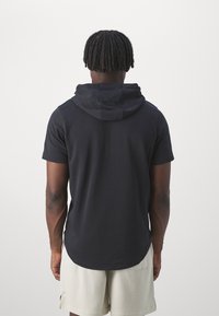 Svart kortärmad hoodie med rundad nederkant och en dubbel-lager crossoverhuva. Slät textur, enkel design och inga synliga mönster.