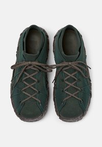 Dark green sneakers with a textured mesh upper and brown laces lie flat against a white background, showcasing unique design details.