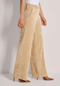 Beige corduroy wijde broek met verticale strepen, voorzien van zakken aan de voorkant, een hoge taille en gecombineerd met bruine puntige hakken.