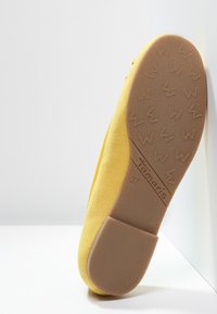 Žlutá nubuková bota s kulatou špičkou a plochou, texturovanou gumovou podešví. Na podešvi je vytištěno jméno značky "Tamaris". Velikost 37.