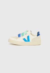 Biały sneaker z zamszowymi detalami, wyposażony w niebiesko-zielone paski na rzepy i niebieski obcas. Zaokrąglony nosek i teksturowana gumowa podeszwa.