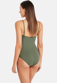 Kostium kąpielowy jednoczęściowy w kolorze oliwkowej zieleni z regulowanymi cienkimi ramiączkami, gładką tkaniną i średnim wycięciem na plecach, charakteryzujący się minimalistycznym designem.