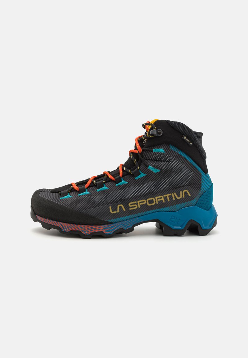 Zwarte wandelboot met een gestructureerde bovenkant, felle oranje en teal accenten, duurzame rubberen zool en een opvallend merkimpressie in goud.