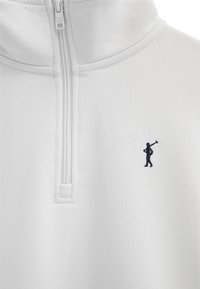 Witte sweater met kwart-ritssluiting en een kleine marineblauwe geborduurde figuur die een polo-knuppel draagt op de linkerborst.