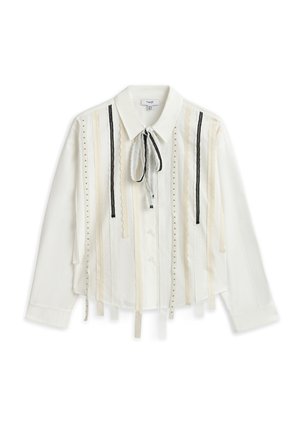 Chemise blanche boutonnée avec des rayures verticales en dentelle et rubans de tissu, finie par un col noué et des manches tombantes.