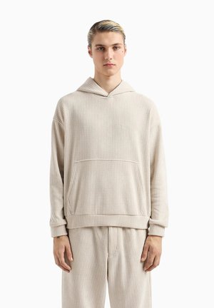 Felpa beige a coste con tasca frontale, vestibilità rilassata e cappuccio regolabile con coulisse. Presenta una consistenza morbida e maniche ampie.