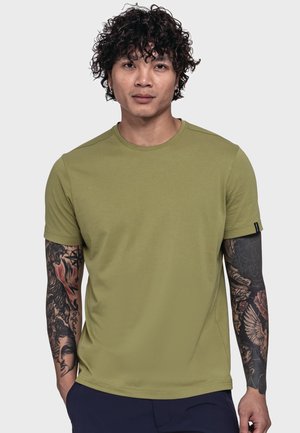 Olivgrünes T-Shirt mit kurzen Ärmeln aus weichem Stoff, mit rundem Ausschnitt und schlankem, taillierten Schnitt. Auf den Armen sind kunstvolle Tattoos sichtbar.