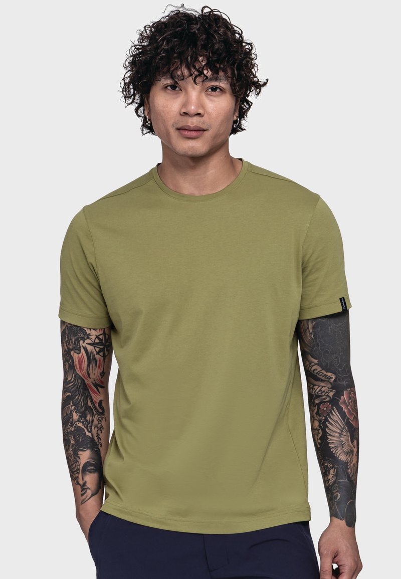 Olivgrünes T-Shirt mit kurzen Ärmeln aus weichem Stoff, mit rundem Ausschnitt und schlankem, taillierten Schnitt. Auf den Armen sind kunstvolle Tattoos sichtbar.