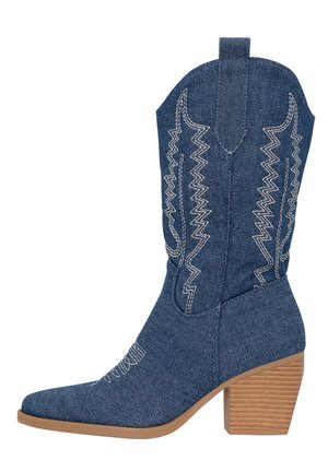 Denim cowboy boot with pointed toe and tapered shape, featuring white zigzag stitching and a stacked wooden heel.