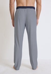 Heren pyjamabroek met een marineblauw en wit gestreept patroon, voorzien van een elastische tailleband en een relaxte pasvorm. Zachte stof en rechte snit.