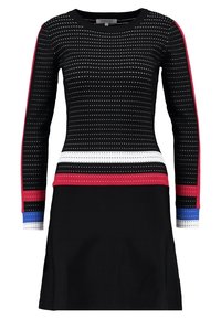 Musta pitkähihaisen neulemekko, jossa on pieniä valkoisia neliöitä, punaisia ja valkoisia rasteja vyötäröllä ja hihansuissa sekä sinisiä yksityiskohtia hihansuissa.