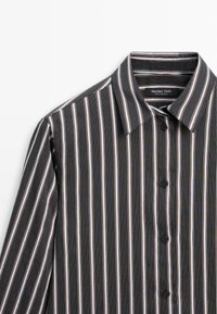 Chemise noire à manches longues avec des rayures verticales blanches et beiges et un col classique, étiquette indiquant Massimo Dutti.