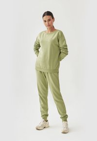 Olijfgroene sweatshirt en bijpassende joggingsbroek van zachte stof, met een ronde halslijn en elastische manchetten voor een relaxte pasvorm.