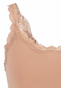Nude cami met delicate kantafwerking langs de halslijn en schouderbanden, gekenmerkt door een soepel, rekbaar materiaal en een aansluitend ontwerp.