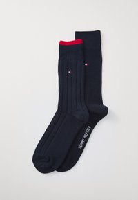 Chaussettes bleu marine avec texture côtelée et tête rouge. Présente un petit détail de logo en bleu, blanc et rouge. Marque "TOMMY HILFIGER" sur la semelle.