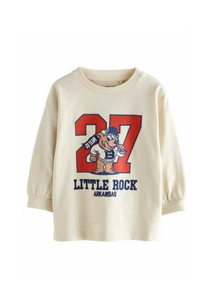 Sweatshirt crème avec de longues manches bouffantes. Présente un graphique coloré d'un ours et le texte "27 LITTLE ROCK ARKANSAS" en bleu et rouge.