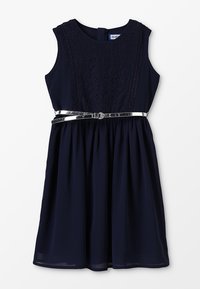 Námořnický modrý šat s krajkovým korzetem, bez rukávů a s rozšířenou sukní. Obsahuje stříbrný pásek v pase pro lepší detail.