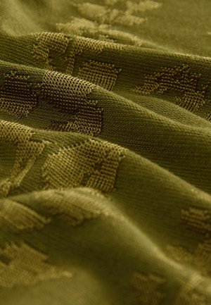 Texturerad grön tyg med ett subtilt mönster, som har varierande nyanser av oliv och en mjuk väv, vilket visar en flödande häng.