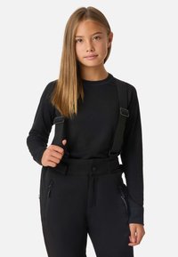 Musta pitkähihainen paita, jossa on ribbineulosta ja säädettävät mustat henkselit, yhdistetty mustiin housuihin, joissa on sivusauma vetoketputaskulla.