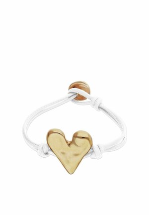 Pulsera de cordón blanco con un charm dorado en forma de corazón y un cierre redondo dorado.