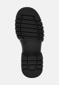 Sole in gomma nera con pattern di battistrada testurizzato, caratterizzato da segmenti rialzati per la trazione e un design della suola arrotondato. Taglia indicata come 37.