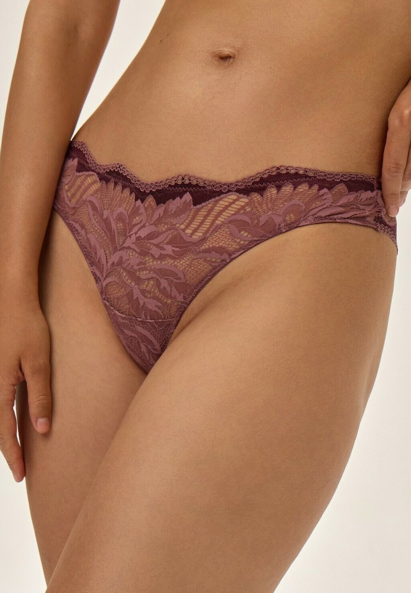 Koronkowe majtki bikini w kolorze mauve z kwiatowymi wzorami, falbaniastymi brzegami i przezroczystym designem. Miękka tekstura z elastycznym pasem.