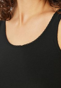 Zwart tanktop met een ronde hals, voorzien van een kantafwerking langs de rand. De stof is glad en aansluitend, met een eenvoudige uitstraling.
