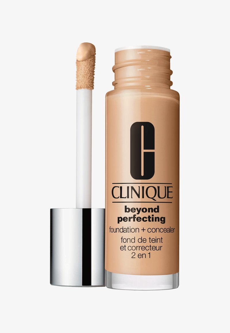 Fond de teint et correcteur Clinique Beyond Perfecting dans un flacon en verre avec un capuchon argenté. Équipé d'un applicateur doux, de couleur beige nude.