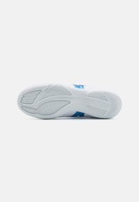 Suola di scarpa sportiva bianca con accenti blu. Presenta una suola in gomma texture e un battistrada motivo per una maggiore trazione.