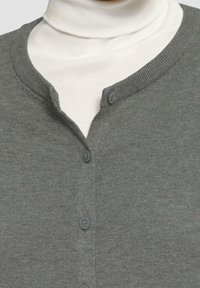 Grauer Pullover mit einem Henley-Ausschnitt, gerippten Kanten und zwei dunklen Knöpfen auf der Vorderseite, über einem weißen Rollkragenpullover getragen.
