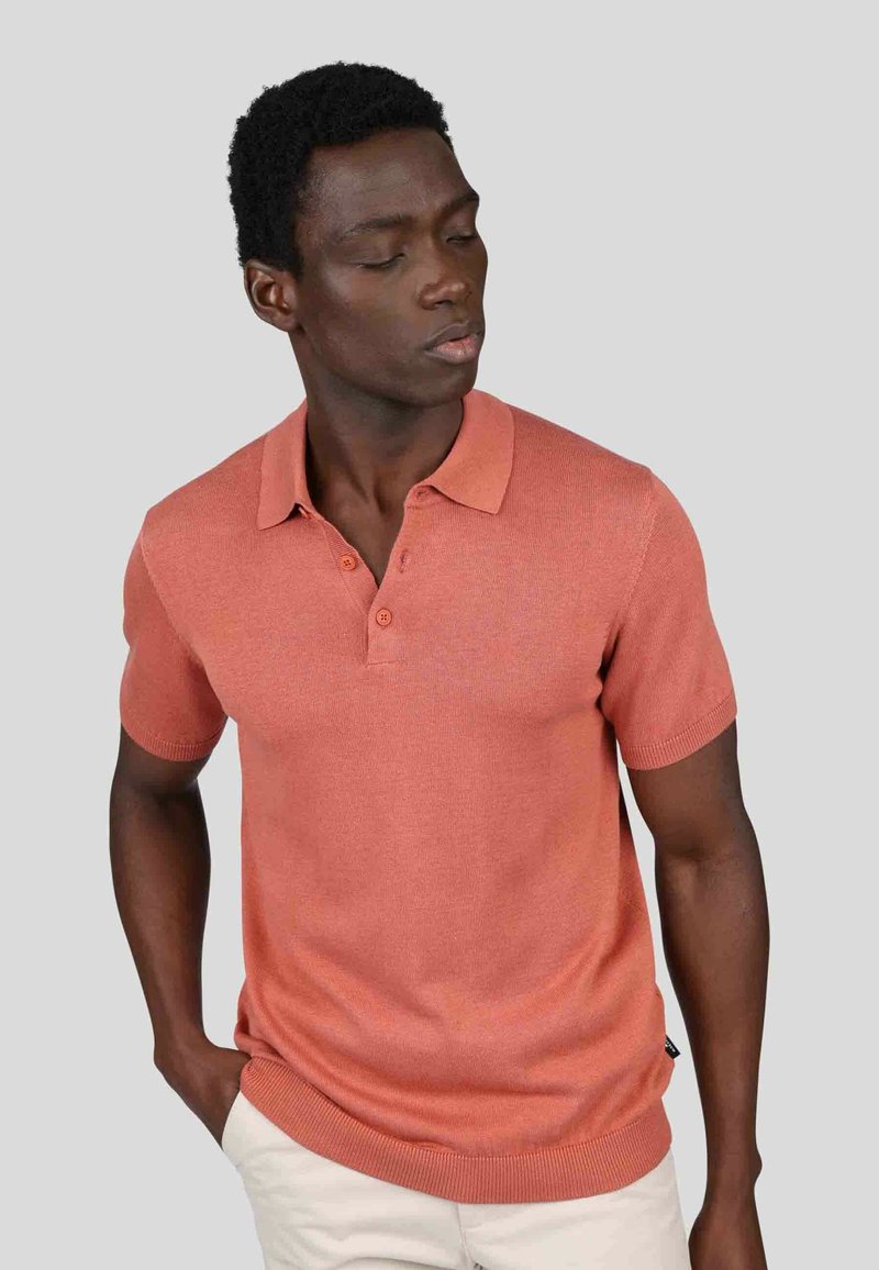 Polo à manches courtes en tissu tricoté corail avec col évasé, patte de boutonnage à trois boutons et ourlet côtelé, conçu pour une silhouette ajustée.