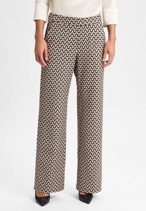 Weite Hose aus beigem Stoff mit einem schwarzen Wellenmuster. Glatte Textur, elastischer Bund und minimalistisches Design ohne sichtbare Hardware.