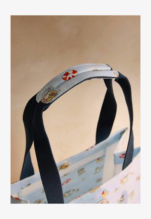 Niebieska torba na ramię z uchwytami z ciemnoniebieskiej tkaniny oraz osłoną na rączkę ozdobioną czerwonymi i białymi ilustracjami koła ratunkowego i łodzi.