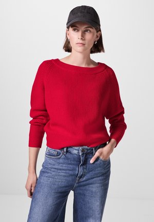 Rød ribbet sweater med rund hals og trekvartærmer, parret med blå høj talje jeans. Struktureret stof, enkelt design.