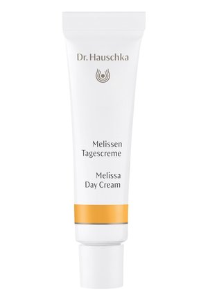 Tube blanc avec des accents orange et gris, étiqueté "Crème de Jour Melissa Dr. Hauschka", avec un capuchon à charnière et un design minimaliste.