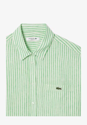 Camisa de botones a rayas verdes y blancas con cuello, que presenta un pequeño logotipo de cocodrilo bordado en el bolsillo izquierdo del pecho. Corte oversize.