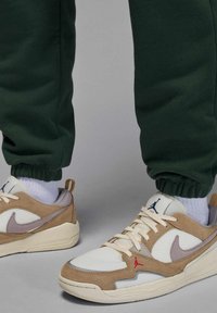 Sneakers con design in mesh e suede, caratterizzate da tonalità beige, bianco e grigio. Accenti rossi e blu, con suole e lacci strutturati.