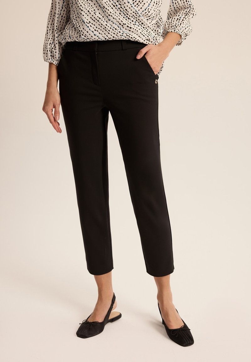 Czarne dopasowane spodnie o kroju slim i skróconej długości. Posiadają pas, kieszenie boczne oraz subtelny metaliczny akcent.