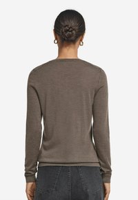 Brązowy sweter z długim rękawem i okrągłym dekoltem, z prążkowanymi mankietami i dołem, wykonany z miękkiego, teksturowanego materiału, pokazany od tyłu.