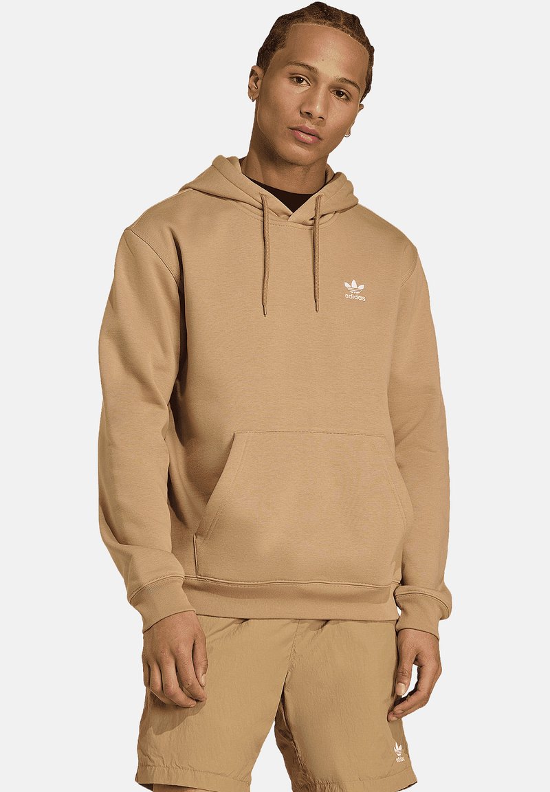 Tankleurige hoodie van zachte stof met een kangoeroezak, capuchon met trekkoord en een klein wit Adidas-logo op de borst.
