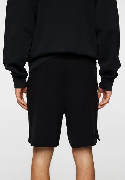 Sorte jerseyshorts med en avslappet passform, elastisk midje og sidelommer. Har et rent, sømløst design med en myk tekstur.