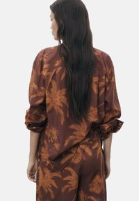 Camicia casual marrone con stampa a foglie di palma in tutte le tonalità di arancione, con maniche arrotolate e una silhouette rilassata.