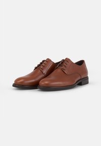 Chaussures habillées en cuir marron avec fermeture à lacets, bout arrondi, talon bas et texture lisse. Présentent un design minimaliste et une construction robuste.