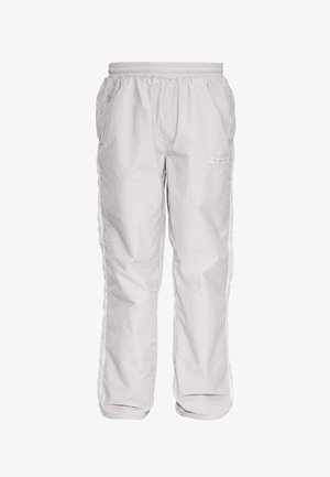Pantalon blanc ample avec taille élastique et poches latérales, présentant un logo brodé subtil sur la cuisse supérieure.