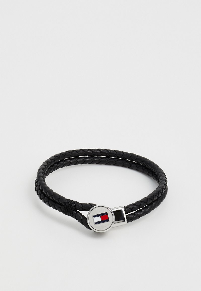 Must mustribaelne nahkpael, millel on hõbedane lukk, kus on ümmargune logo punaste ja siniste detailidega. Sile tekstuur, kahepaelne disain.