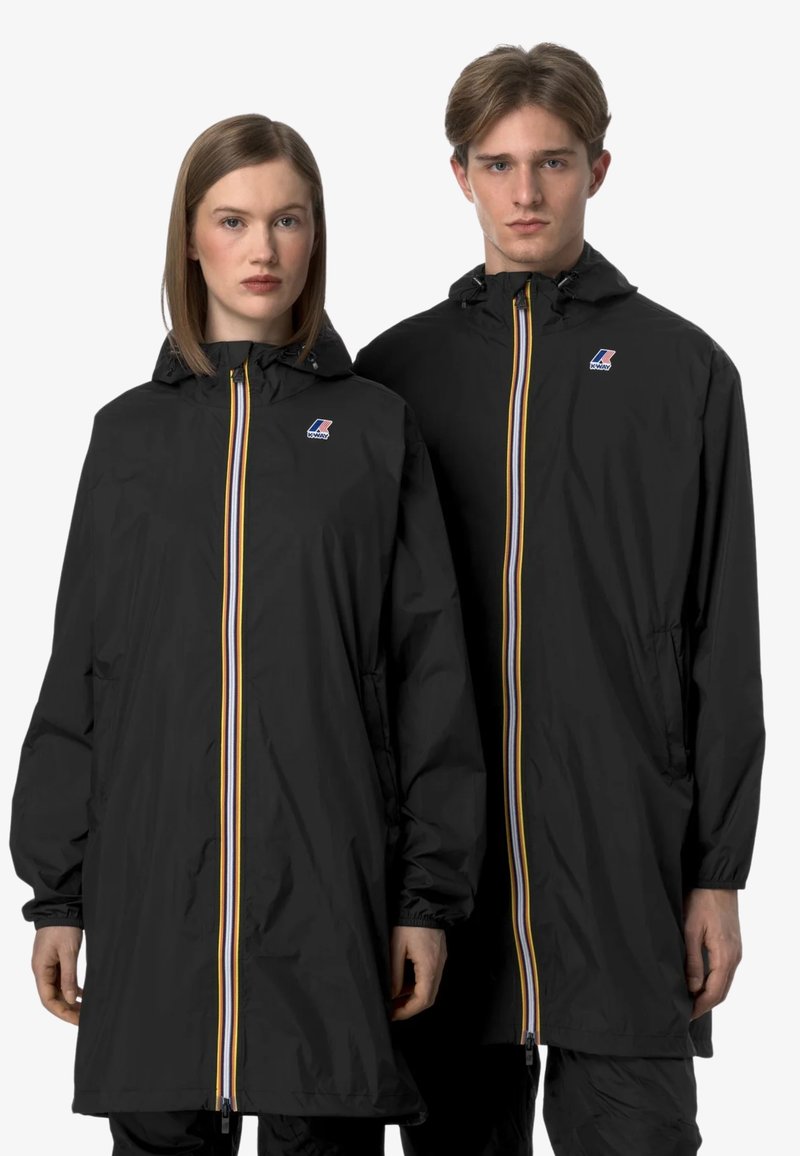 Des imperméables noirs avec capuches, dotés d'une fermeture éclair centrale avec des rayures jaunes et blanches et des accents de logo sur la poitrine.