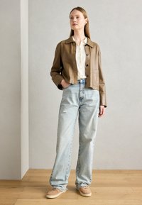 Brun lærjakke, lys knapp-opp skjorte, høy midje lys blå denimjeans og beige sneakers. Enkel, uformell design.