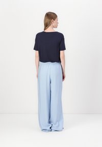 Camisa de manga corta en color navy combinada con pantalones de pierna ancha de un tono azul claro. Los pantalones tienen una cintura elástica y una textura de tela suave y fluida.